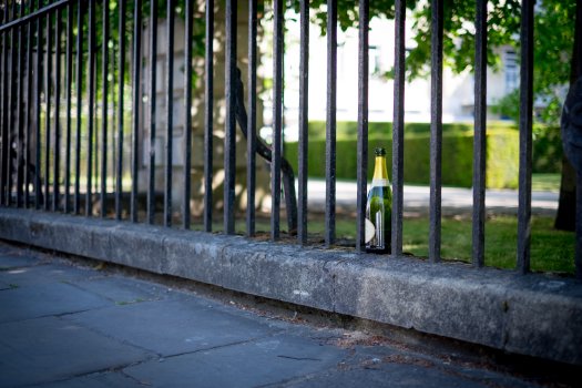 An empty bottle of champagne wedged into a fence