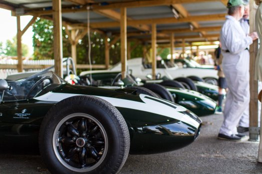 A view of a line of vintage cigar shaped formula one cars in a row under an anwning.