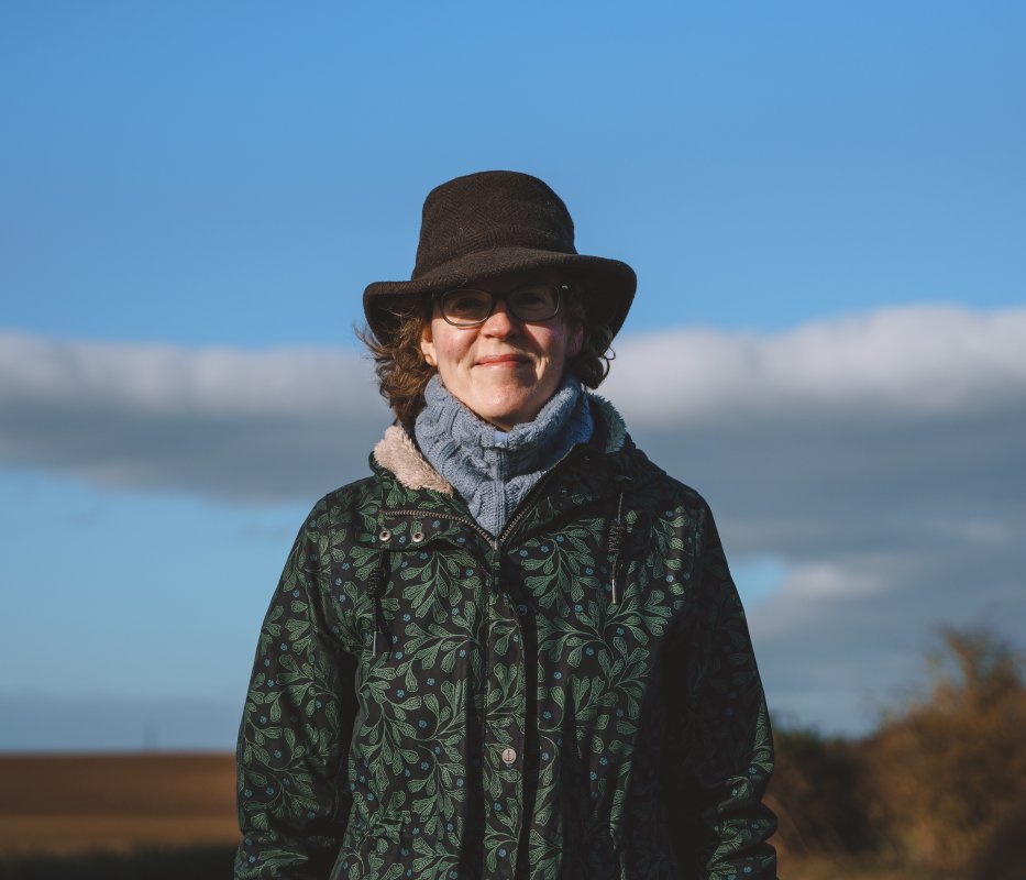 A head and sholders portait of Laura, wrapped up warm on a sunny winter day with the fens behind her.