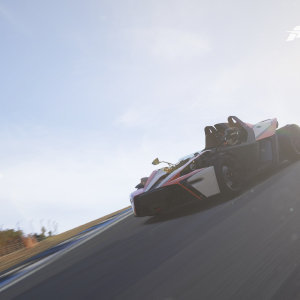 A screenshot of a KTM Crossbow track car just cresting a hill with the sun behind it.