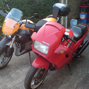 The old red Ducati that is going away stood next to the orange Buell Ulysses that replaces it