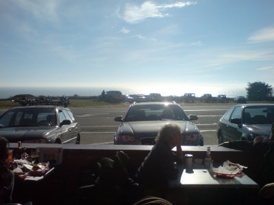 A picture from a cafe next to the road, looking across the road to the pacific ocean.