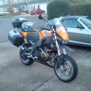 A big yellow and black motorbike sits on the driveway towering over our Smart Roadster.