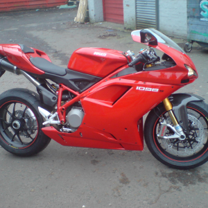 A photo of a big red sports motorbike in the back alley behind the motorbike store.