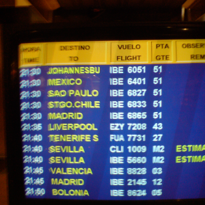 A monitor showing flight departures. The first five flights, going to Johannesburg, Mexico, Sau Paulo, Santiago, and Madrid, are all at the same time and gate.