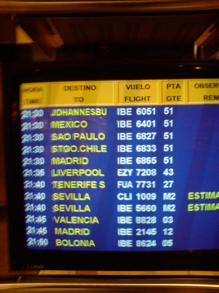 A monitor showing flight departures. The first five flights, going to Johannesburg, Mexico, Sau Paulo, Santiago, and Madrid, are all at the same time and gate.