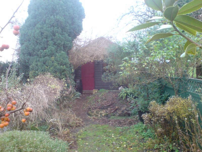 A photo of a summer house at the end of a garden path.