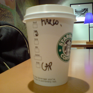 A starbucks coffee cup that has 'CAP' and 'MARCO' written on the side