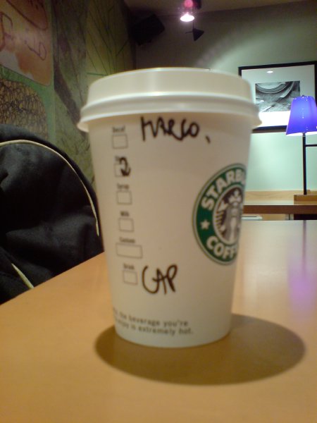 A starbucks coffee cup that has 'CAP' and 'MARCO' written on the side