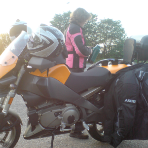 Laura pouring coffee from a thermos into two coffee cups sat on the seat of a motorbike