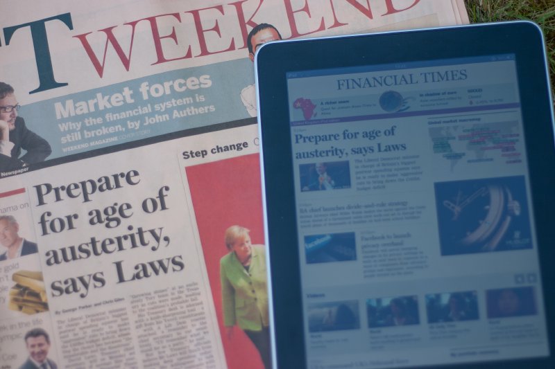 A photo of the FT news-paper, with an iPad placed over it, showing the same front page on the FT app.