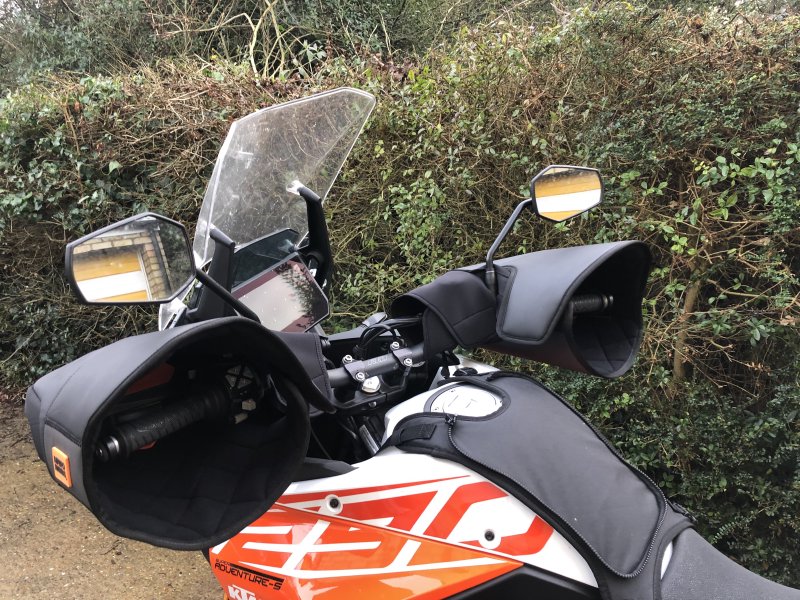 A picture of the front, top half of my KTM motorcycle, showing both ends of the handlebars to be encased in bags, each with an opening for my respective hand to access the controls.
