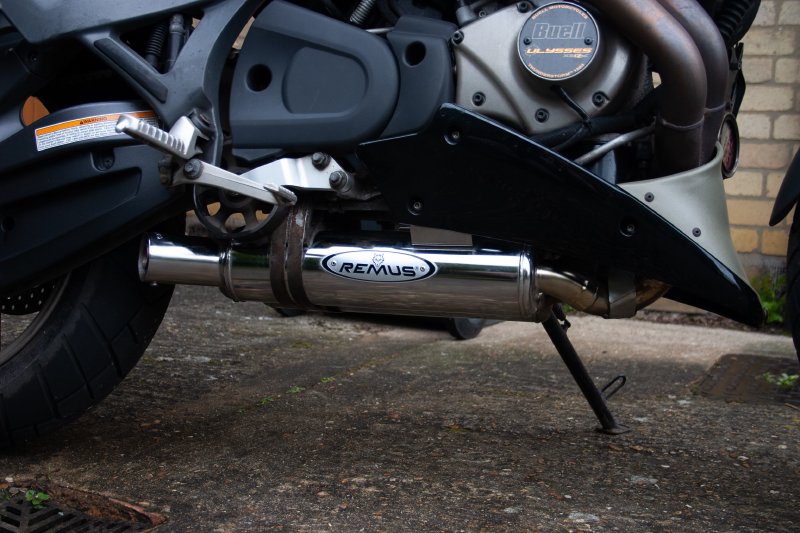 A shiny chrome new exhaust with a 'Remus' logo on it mounted to the bottom of motorbike.