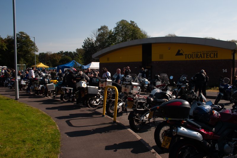 A photo of countless adventure motorcycles and their owners part outside the industrial unit that is Touratech's Wales branch.