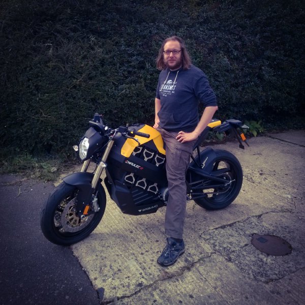 Me sat on a small yellow and black electric motorbike parted on our driveway.