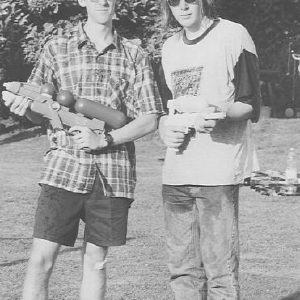 Me and Will standing in a garden both clutching super-soaker water pistols.