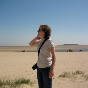 Laura stood on a sun-lit beach smiling off to the side