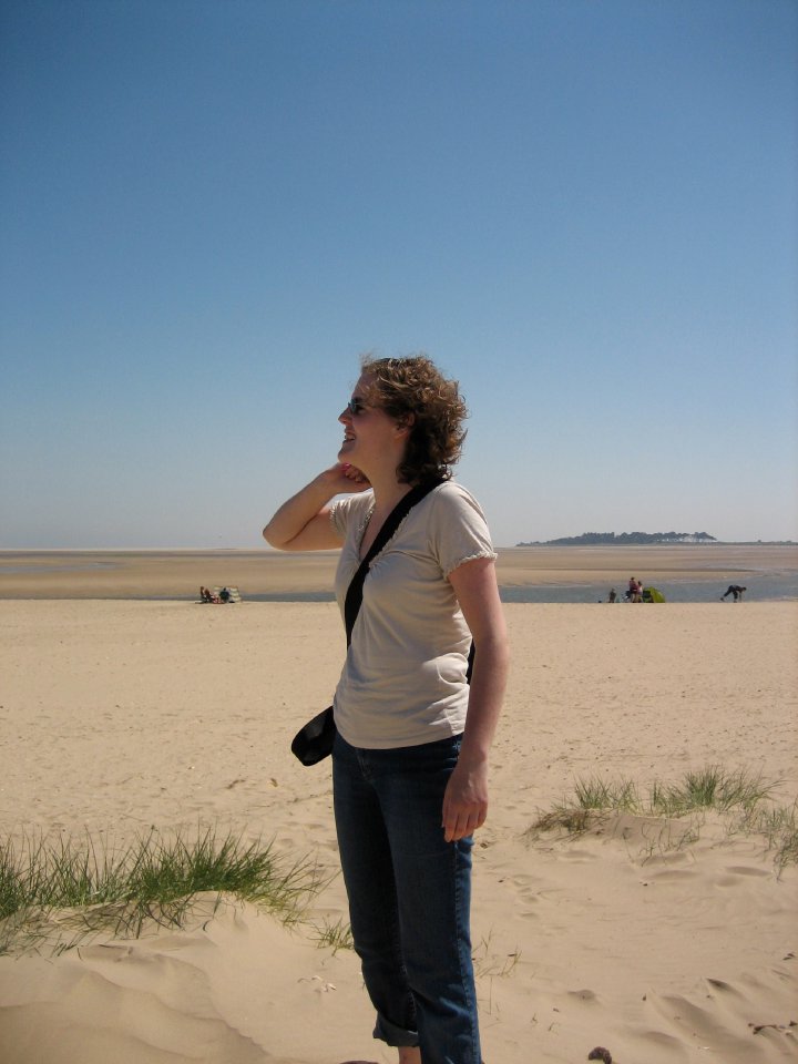 Laura stood on a sun-lit beach smiling off to the side