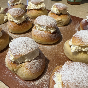 Tolv fräsch semlor på en skärbräda.