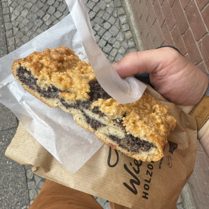 A photo of my hand holding a pastry/cake thing that is filled with a black looking paste in the middle.