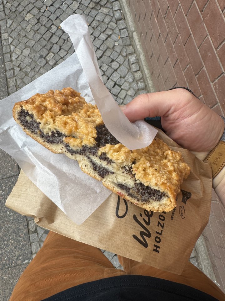 A photo of my hand holding a pastry/cake thing that is filled with a black looking paste in the middle.