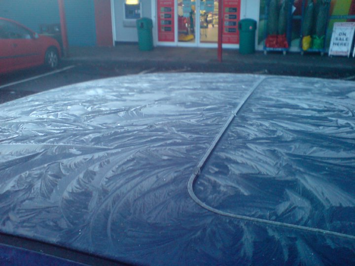 The top of a car is covered with a pretty layer of frost in a very crystaline pattern.