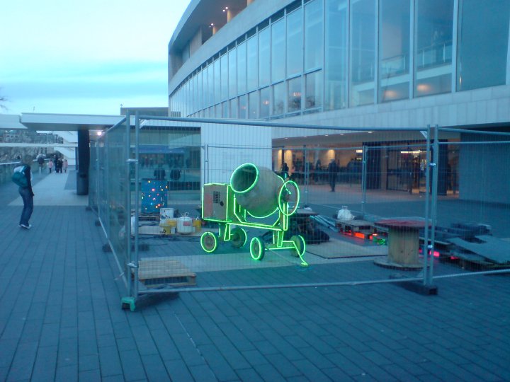 A photo of a cement-mixer that has had green neon lights added around it to emphesise its outline.