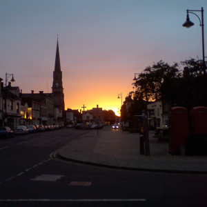 A glowing sunset lights the skyline, leaving St Ives main street in shadow.