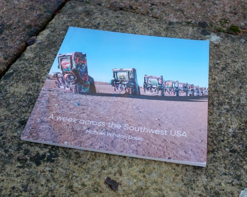 A photo of the cover of the zine, the famous cadillac graveyard, consiting of a doze cadillac cars half-burried nose down in the hard soil.